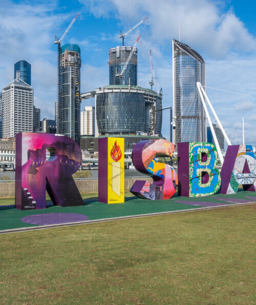 Colourful Brisbane sign at South Bank with CBD skyline and construction cranes