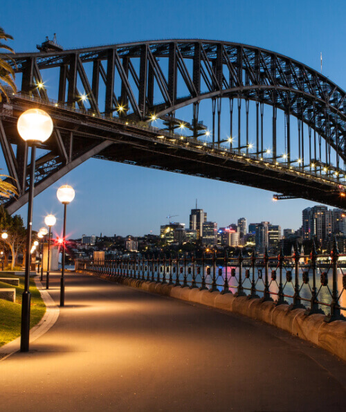 Sydney Harbour Bridge walkway at dusk with city lights
